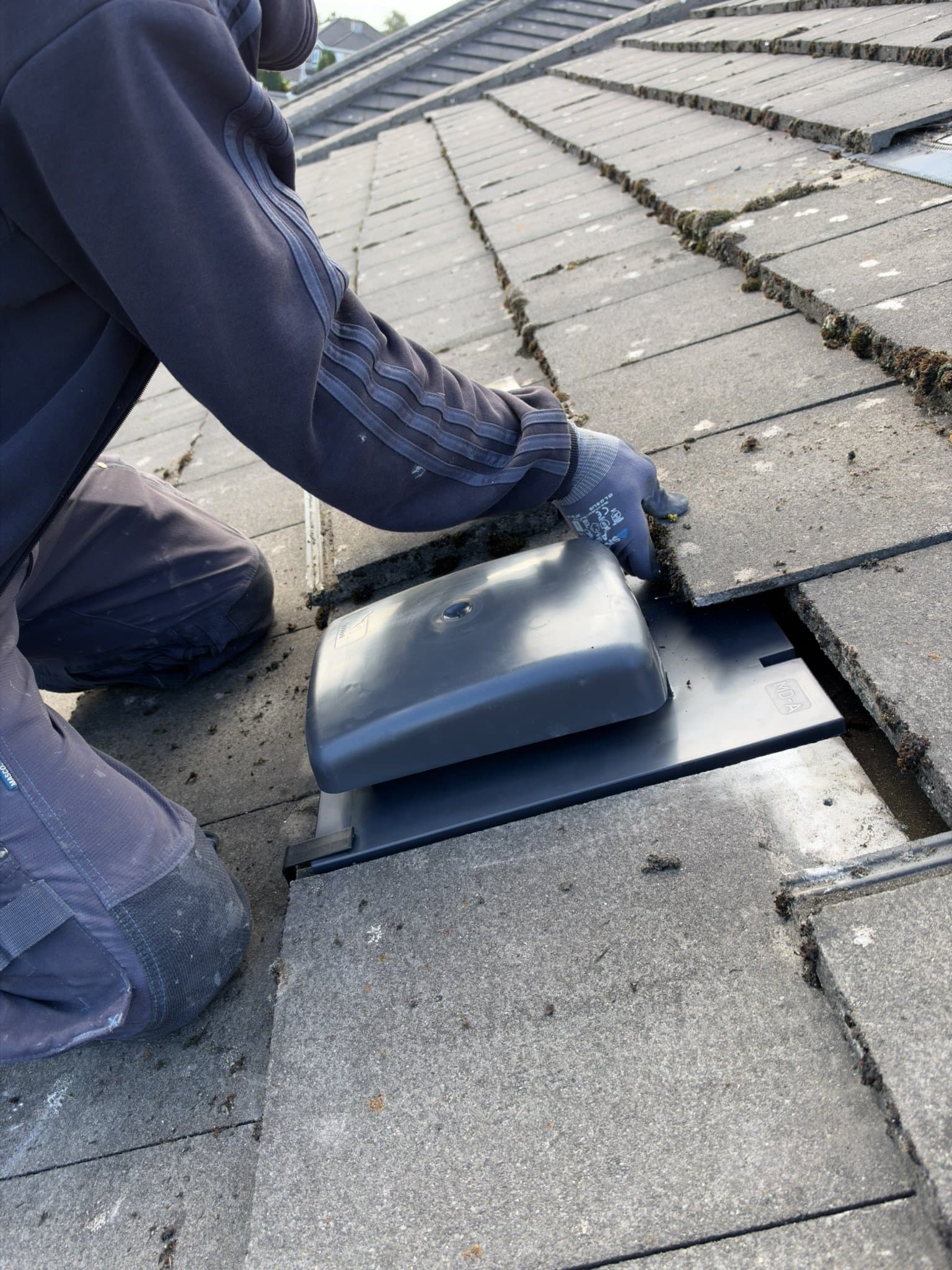 Secure Top Roofing roofer fitting a ventilation tile between the existing roof tiles.