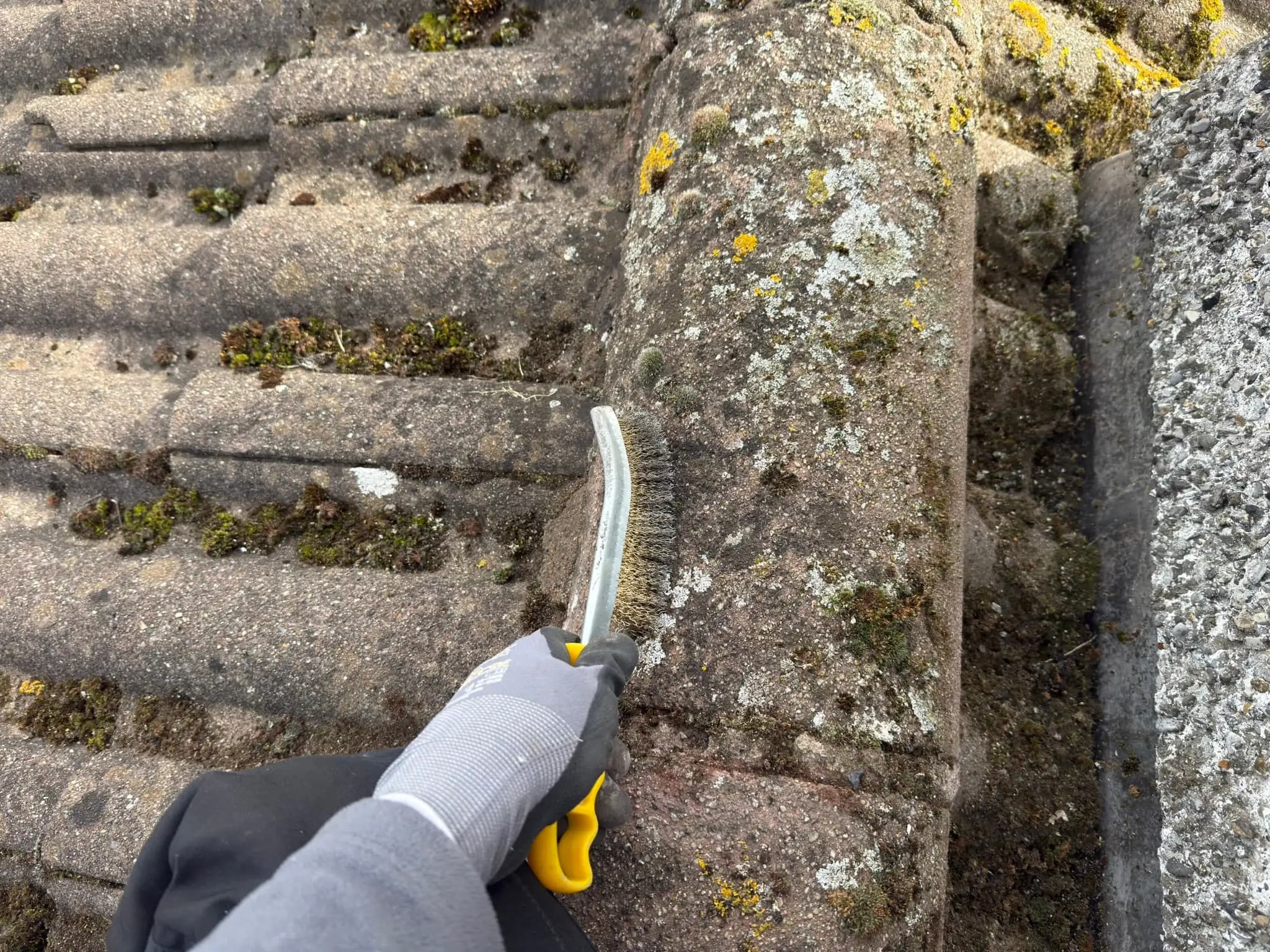 Ridge tile being brushed before repointing in Whitestown.